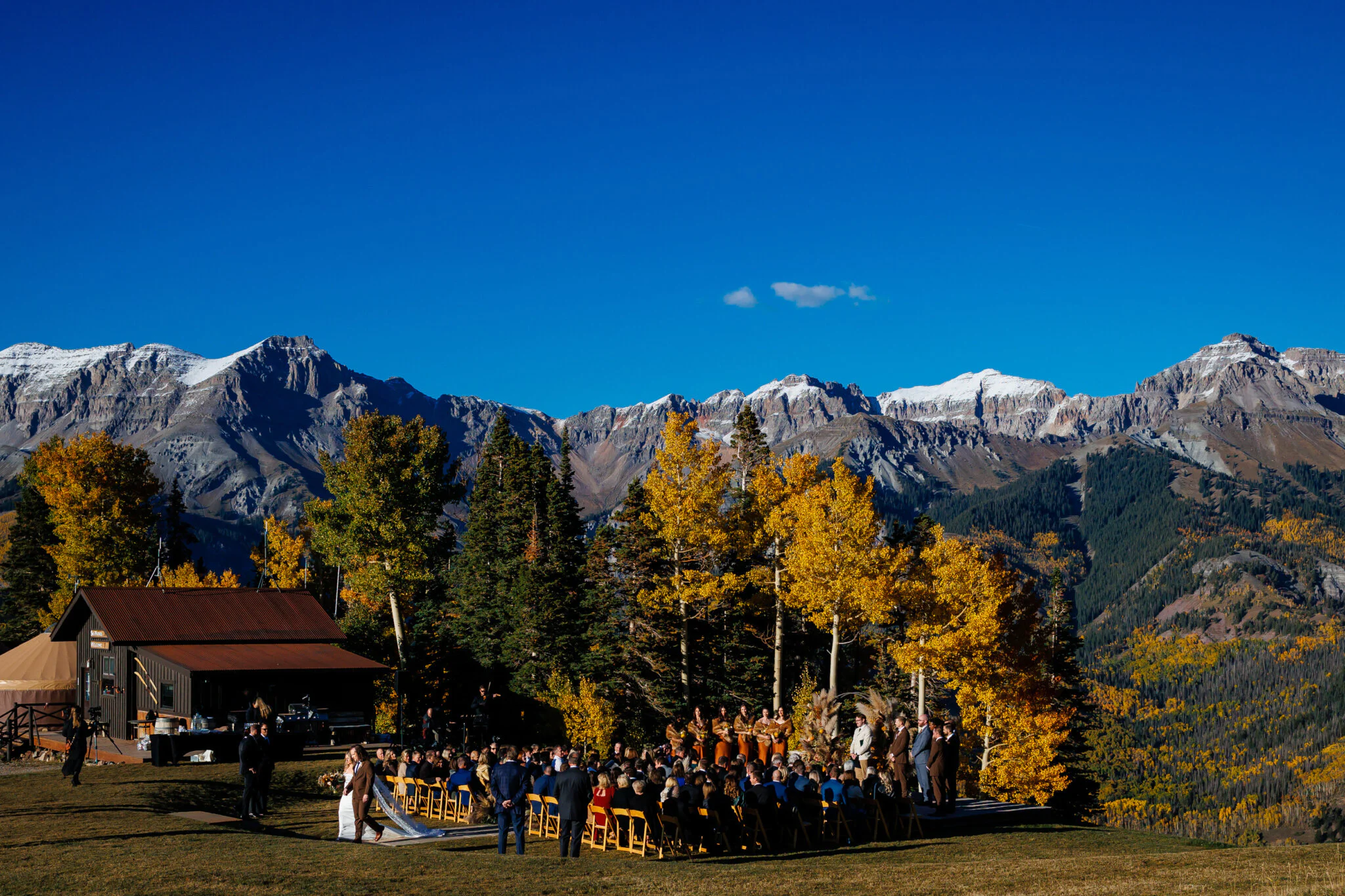 A ceremony at San Sophia Overlook with guests seated in front of aspens and the snow-dusted peaks