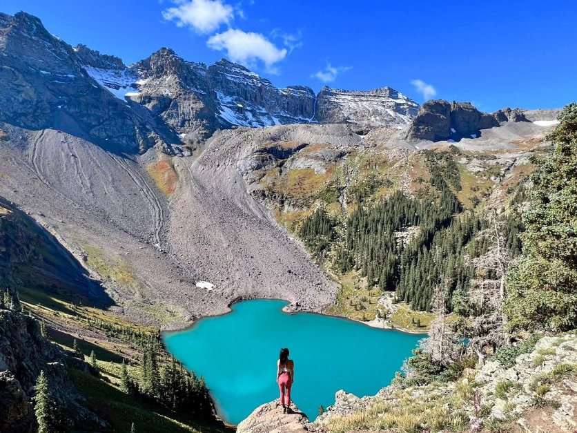 A hiker above the turquoise Blue Lake below rocky peaks