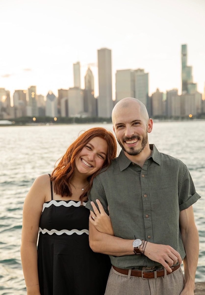 Karli resting her head on Kyle's shoulder, both smiling, by the lake at sunset