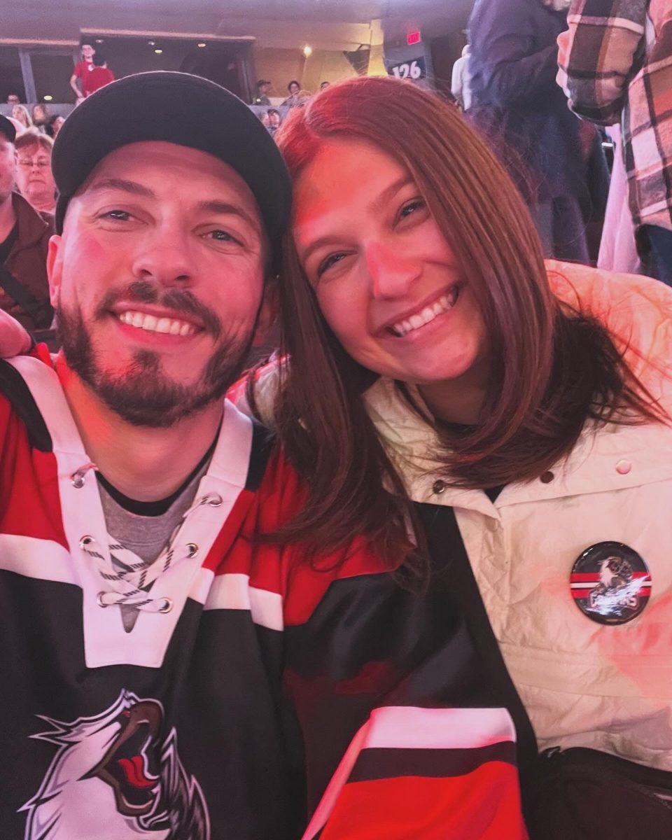 Kyle and Karli smiling together in hockey jerseys at a game