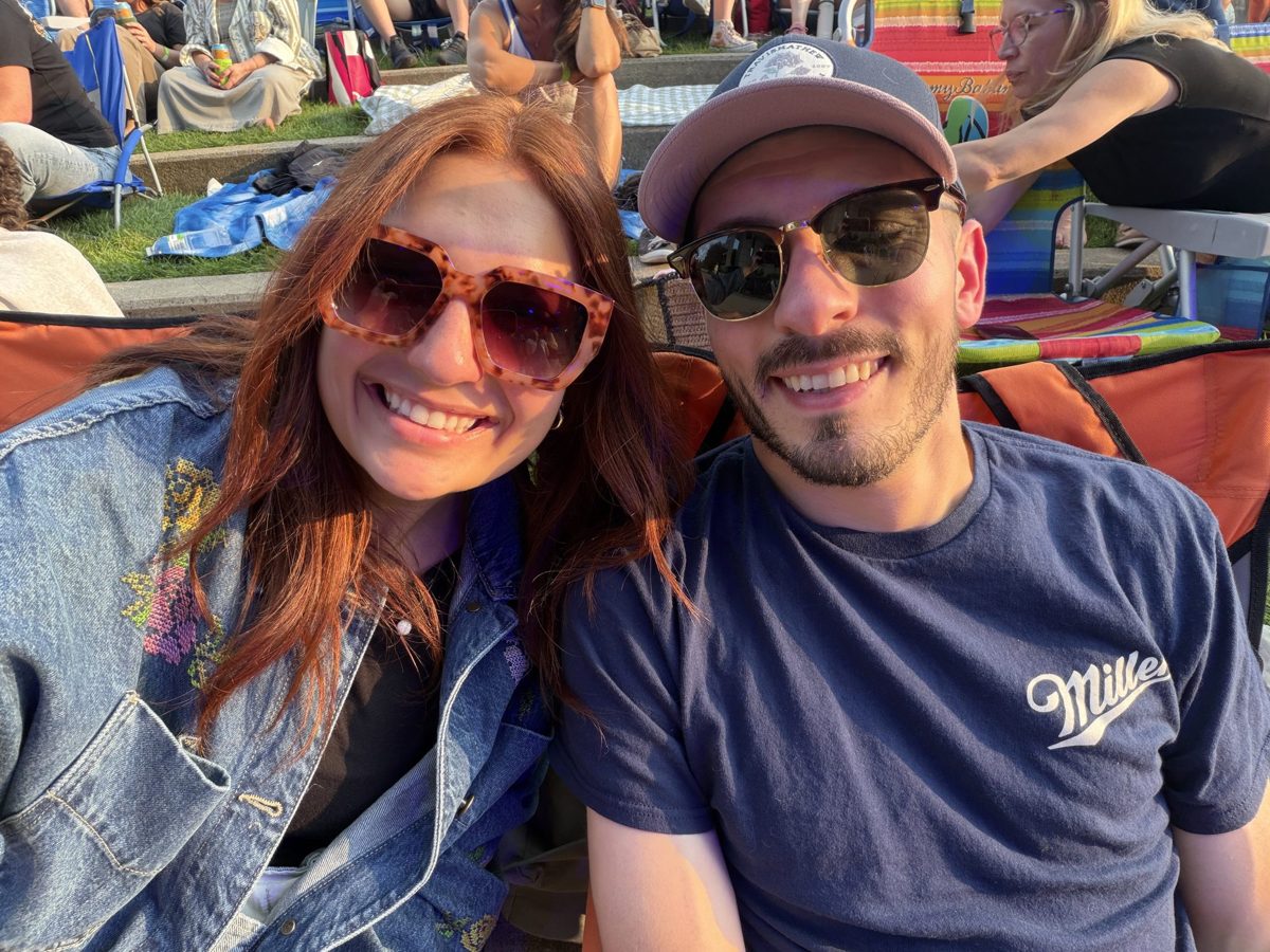 Kyle and Karli in sunglasses smiling together at an outdoor concert on a lawn