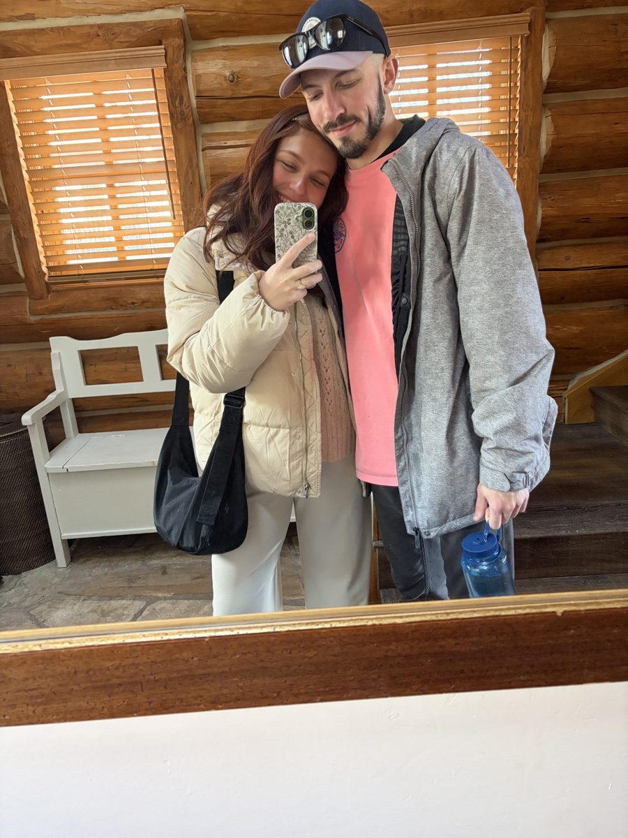 Kyle and Karli taking a mirror selfie in a cozy log-cabin room