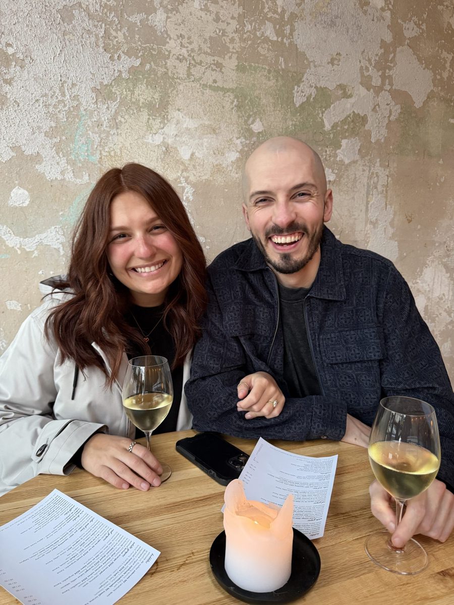 Kyle and Karli smiling at a candlelit table with glasses of white wine