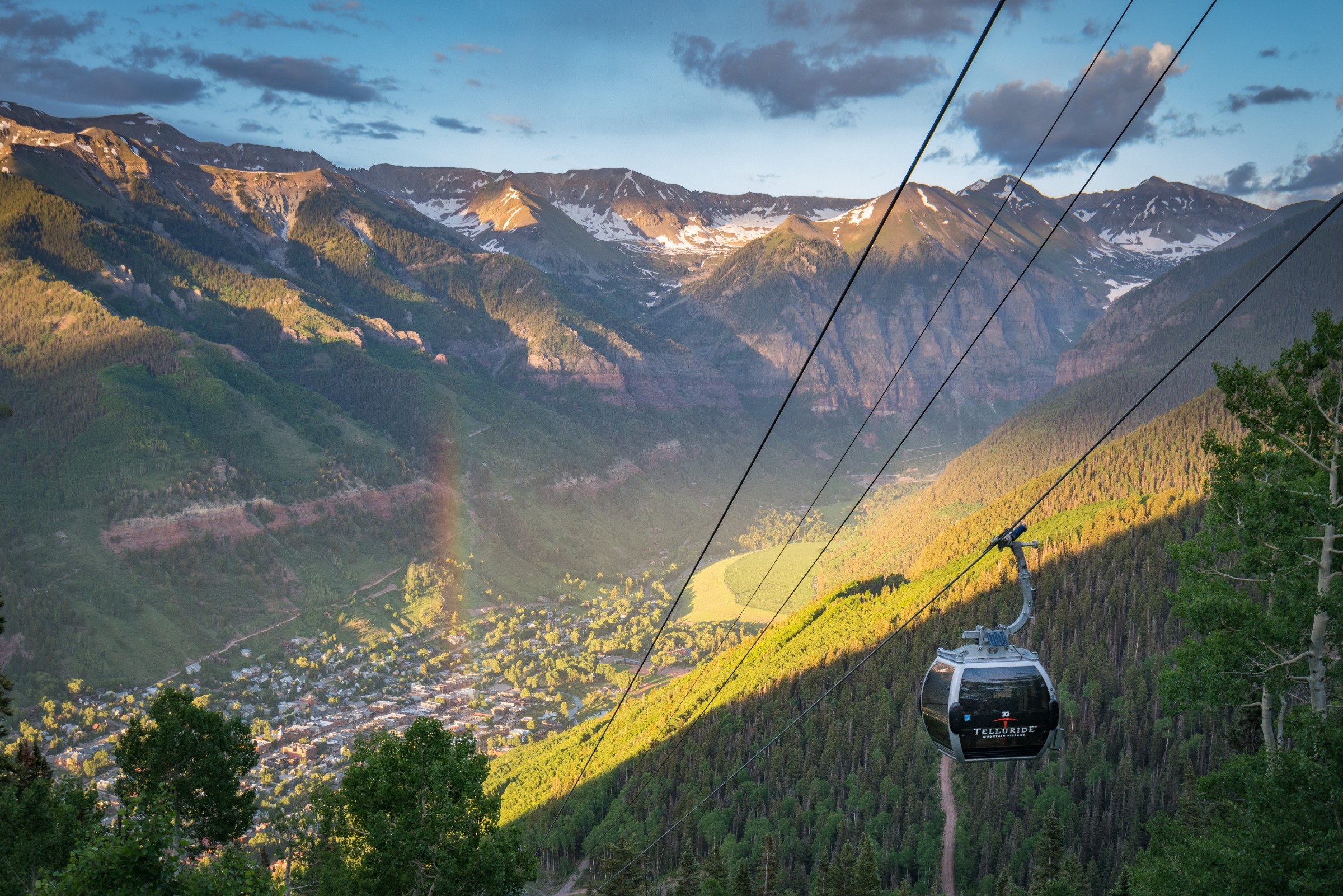 A gondola cabin above the town of Telluride with snow-capped peaks beyond